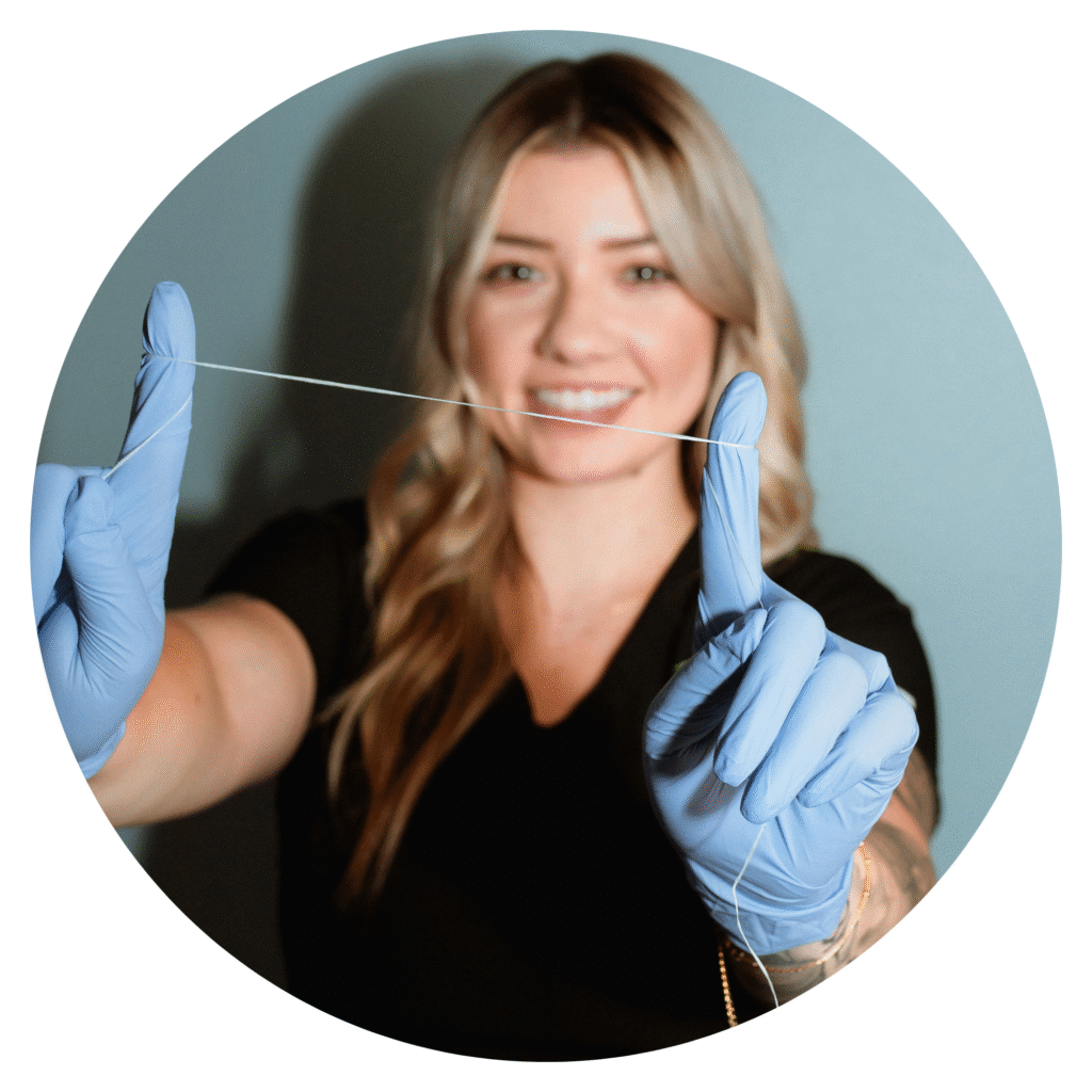 Smiling dental team member in front of Centerpoint Dental holding dental floss to demonstrate proper flossing technique