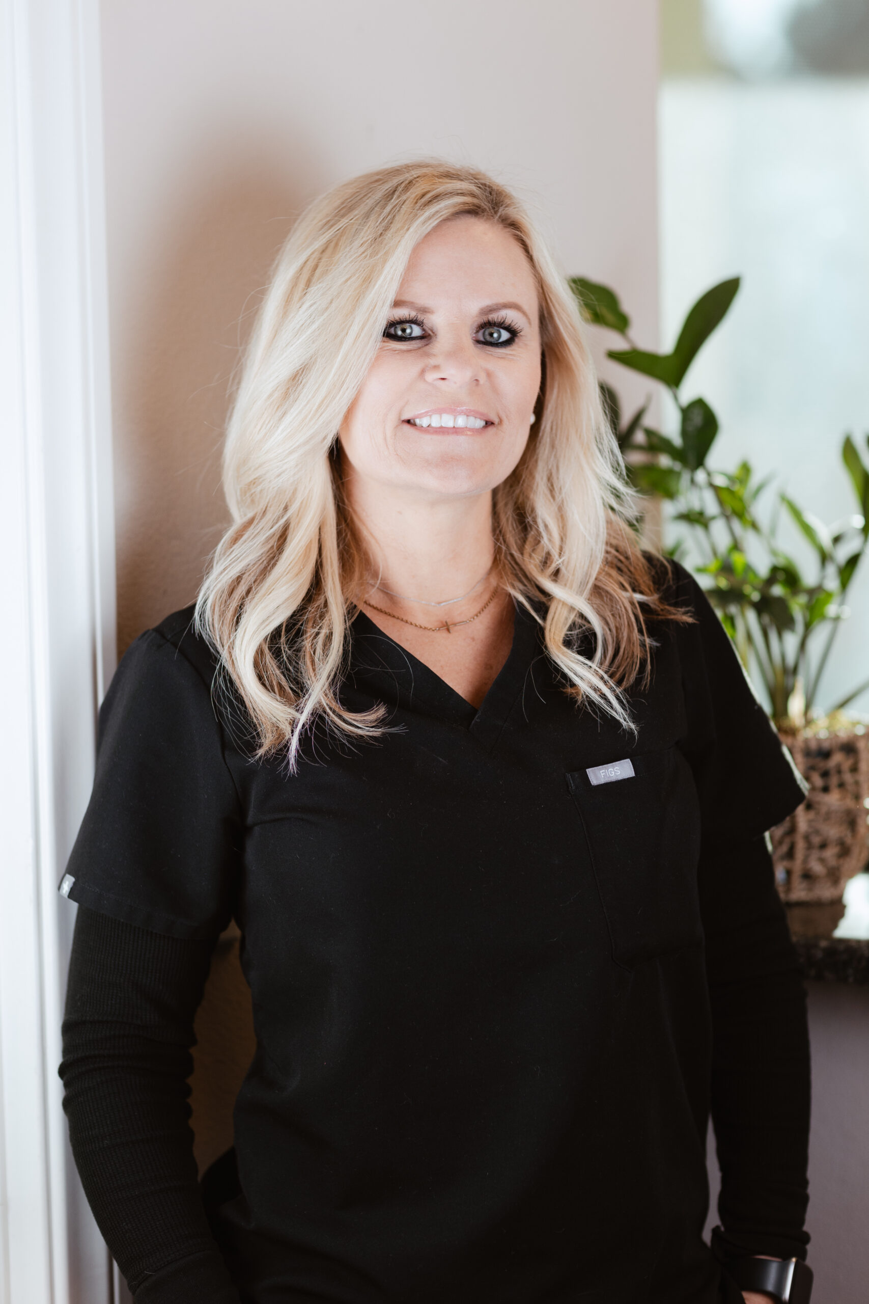 Headshot of Amber, Insurance Coordinator at Centerpoint Dental in Yucaipa, CA, wearing black scrubs and smiling in front of a softly lit background