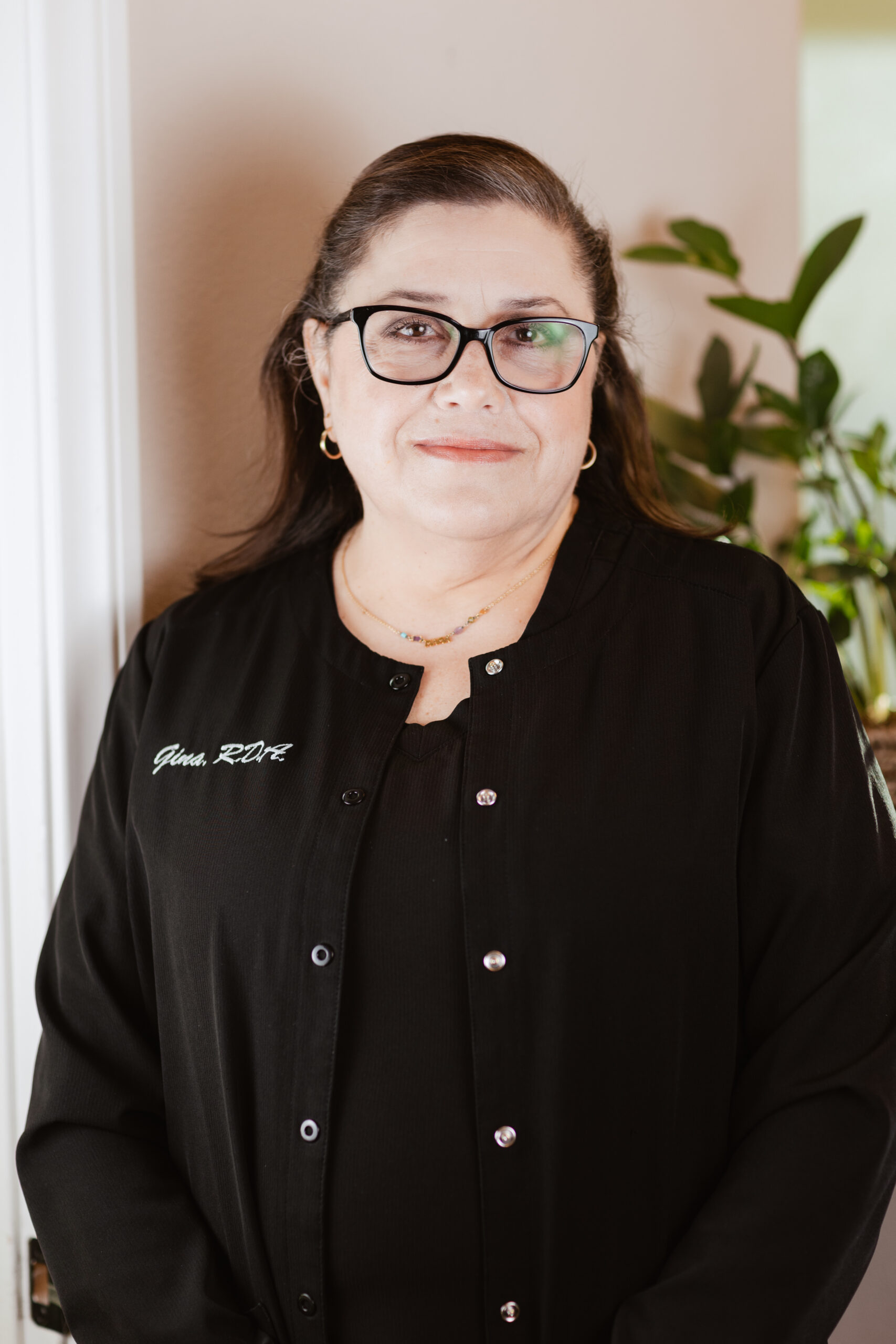 Headshot of Gina, Registered Dental Assistant at Centerpoint Dental in Yucaipa, CA, wearing black scrubs and glasses